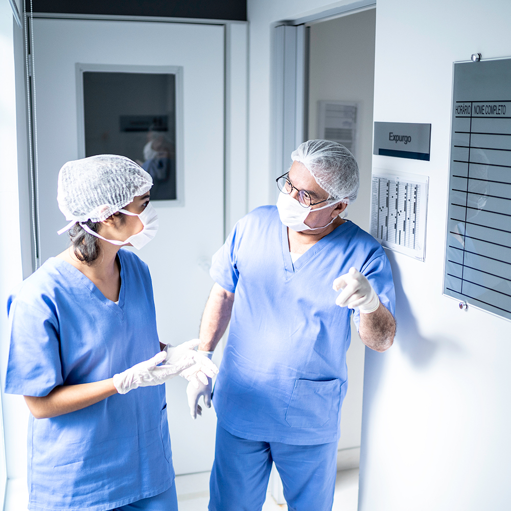 Medical professionals wearing masks and gloves discuss a patient's surgery