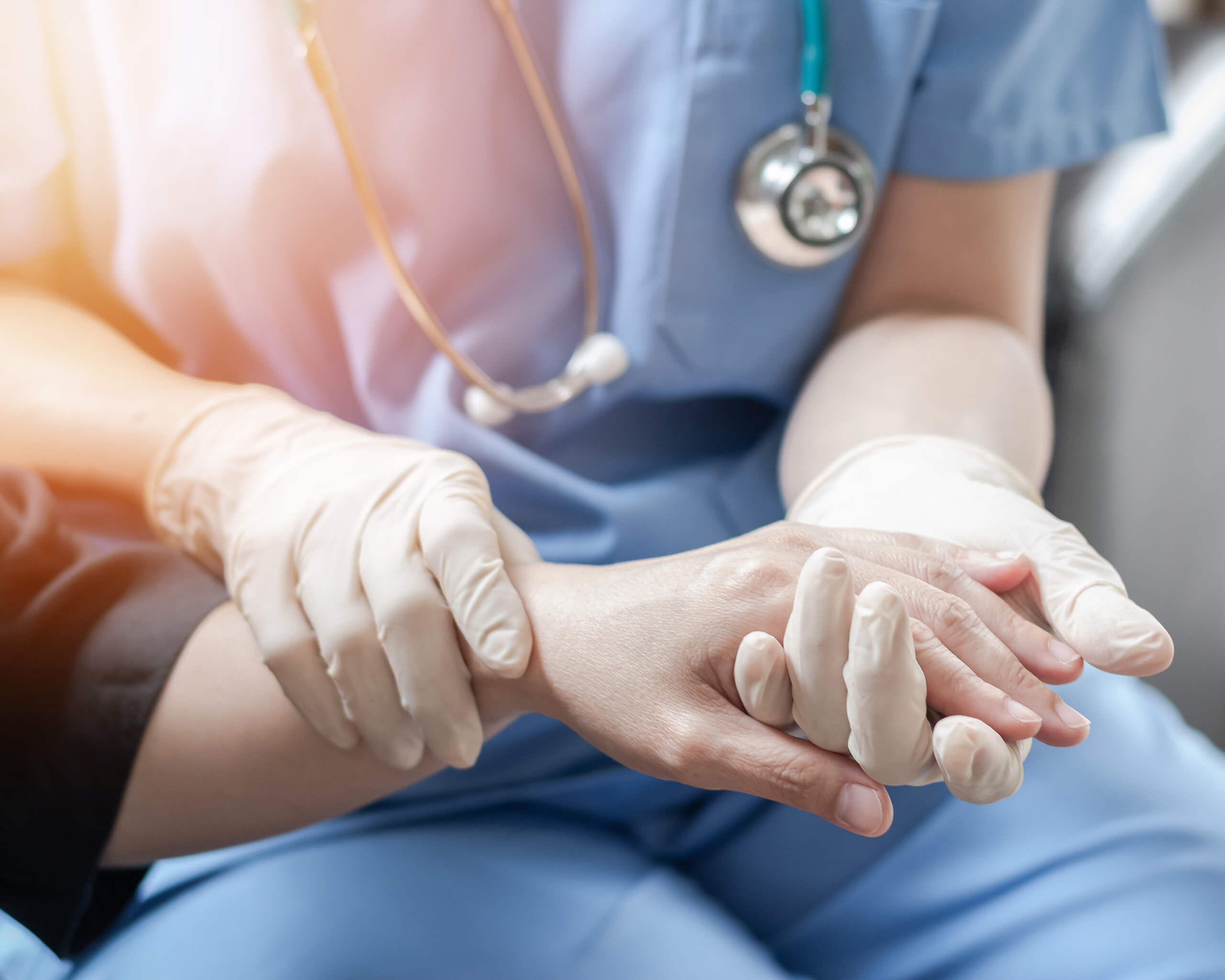 A medical professional holds a patient's hand to represent AAS's Core Values Awards for quarter 1 in 2022.